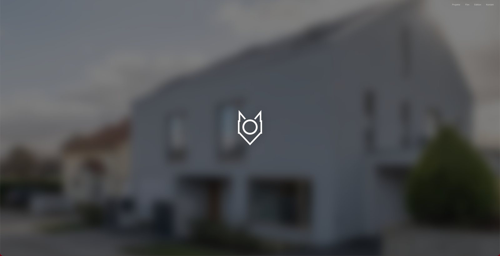 Neue Startseite von WULF Fotografie: unscharf eingeblendetes Architekturfoto mit dem Fuchs-Logo in der Mitte